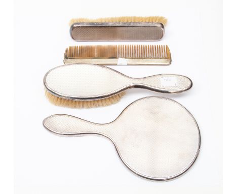 A George V silver four piece dressing table brush set, London 1927, comprising clothes brush, hair brush, mirror and a comb, 