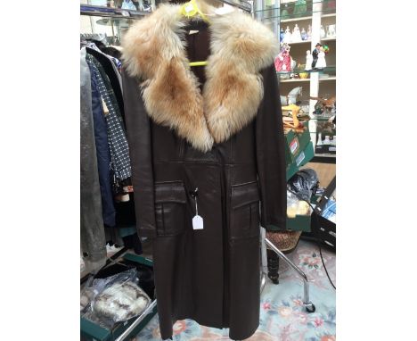 A brown leather full length long coat with a ginger fox fur collar, with a belt, the coat has poachers pockets, the stitch ba