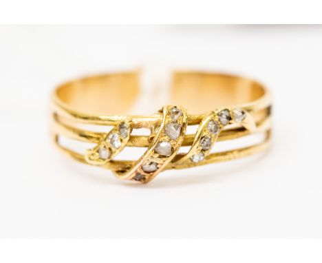 An unmarked yellow metal dress ring set with white stones in a snake like shape over three bars, size P, total gross weight a