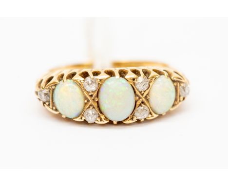 A Victorian opal and diamond 18ct gold ring,  set with three oval opals, with diamond accents, scroll shoulders, ring size M,