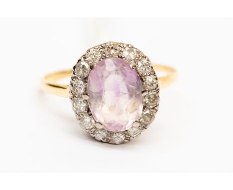A diamond and amethyst dress ring, the central oval stone measuring approx 11mm x 8mm,  with a diamond set surround, unmarked