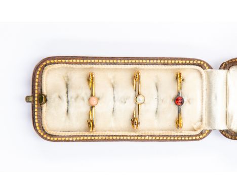 Three unmarked yellow metal and stone set safety pins, each set with a cabochon stone including an opal version, in original 