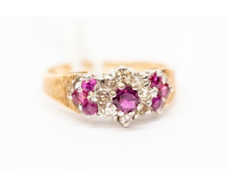 A ruby and diamond cluster ring, set with a central round ruby with a diamond surround along with a further three other rubie