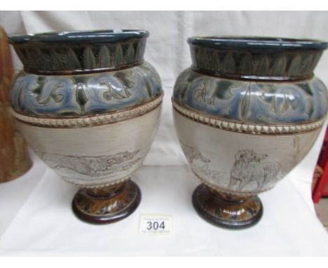 A pair of Doulton Lambeth 1882 Hannah Barlow vases with patterned top and bottom and incised pictures in the panel.  One is a