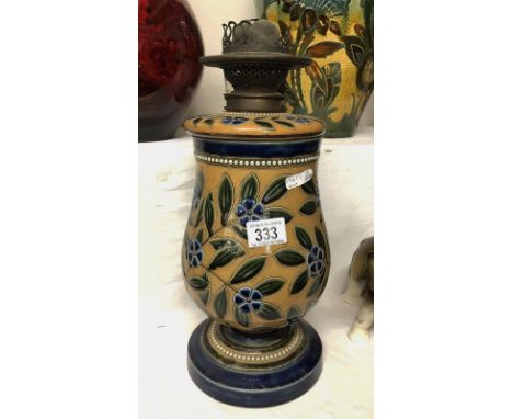 An attractive floral Doulton oil lamp with bank of white dots round the base and rim. Blue flowers and green leaves on a sand