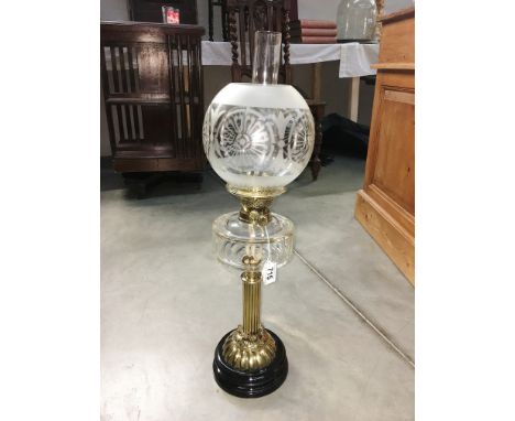 A Victorian oil lamp, circa 1890. Reeded brass pillar lamp sitting on a heavy black ceramic base with cut glass vessel, twin 