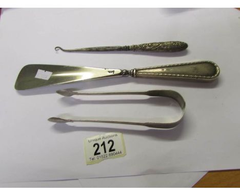 A silver handled button hook, a silver handled shoe horn and silver sugar tongs.