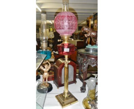 A brass and cranberry glass oil lamp.