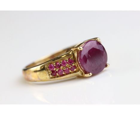 Ruby 9ct yellow gold ring, the central round mixed cut ruby diameter approx 8mm, four claw setting, eight small round mixed c