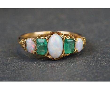 Opal and emerald unmarked yellow gold ring, the three oval cabochon cut graduated precious white opals displaying blue, green