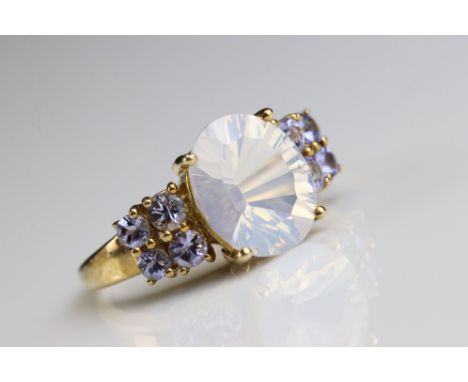 Moonstone and tanzanite 9ct yellow gold ring, the oval mixed cut faceted moonstone measuring approx 11mm x 9mm, four claw set