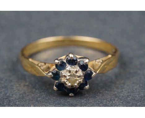Sapphire and diamond 18ct yellow gold and white gold set flower head ring, the central round brilliant cut diamond weighing a
