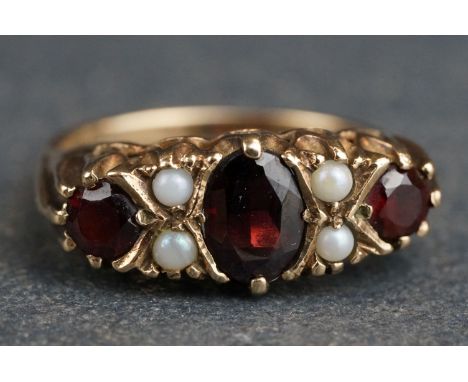 Garnet and seed pearl 9ct yellow gold boat head ring, the principle oval cut garnet measuring approx 6.5 x 5mm, two small rou