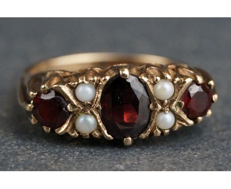 Garnet and seed pearl 9ct yellow gold boat head ring, the principle oval cut garnet measuring approx 6.5 x 5mm, two small rou