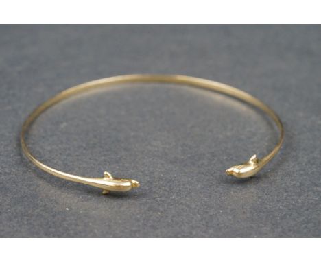 14ct yellow gold bangle, the open terminals modelled as dolphin heads 