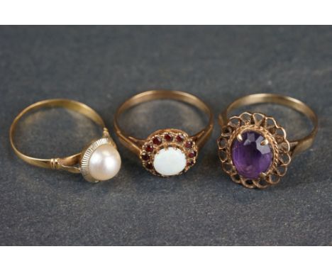 Three dress rings, comprising an opal and garnet 9ct yellow gold cluster ring; cultured pearl yellow metal ring and an amethy