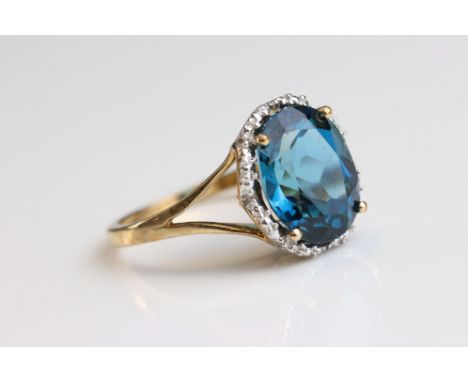 Blue topaz 9ct yellow gold and white gold set ring, the oval mixed cut topaz measuring approx 11mm x 9mm, four claw setting, 