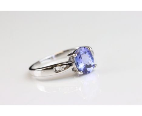 Tanzanite and diamond 18ct white gold ring, the oval mixed cut tanzanite measuring approx 8mm x 6mm, four claw setting, a sma