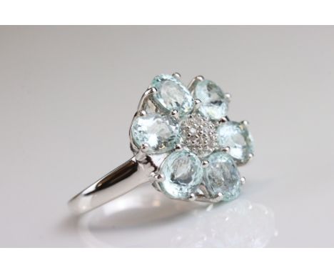 Aquamarine and diamond 18ct white gold flower head ring, the petals formed of six oval mixed cut aquamarine, each measuring a