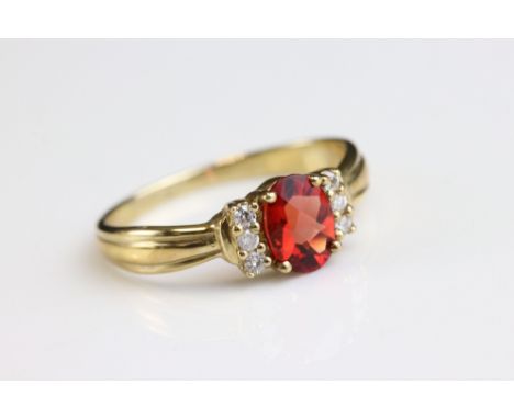 Red stone and diamond 9ct yellow gold ring, the oval mixed cut red stone measuring approx 7mm x 5mm, three small round brilli