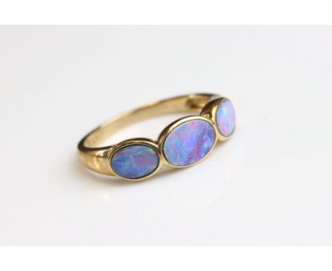 Black opal triplet 9ct yellow gold three stone ring, three graduated oval black opal triplets, the largest measuring approx 7