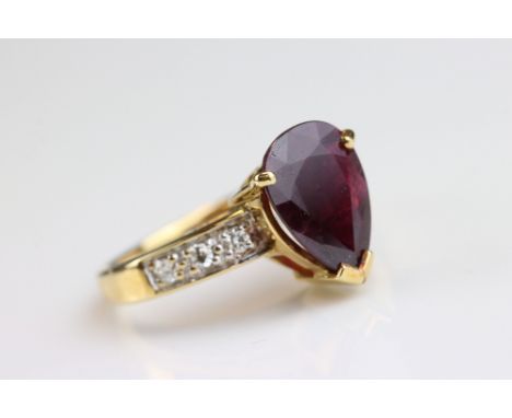 Ruby and diamond 18ct yellow gold ring, the pear shaped mixed cut ruby measuring approx 10mm x 7.5mm, claw setting, three sma