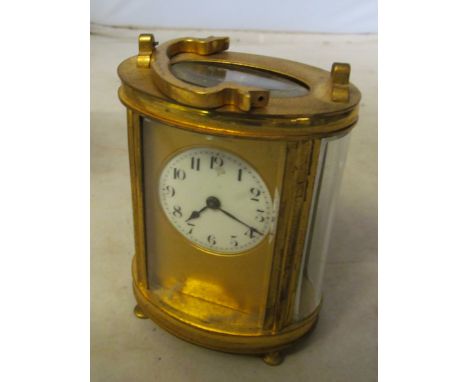 An oval brass carriage clock, the circular dial missing glass panel (not working)
