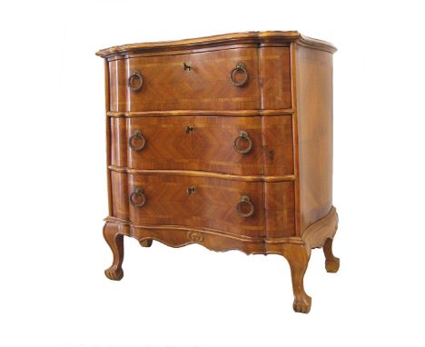 A German style commode, quarter veneered in walnut with feather banding, three long drawers, moulded serpentine front and top