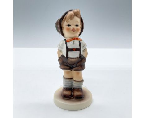 A small hand painted figure of a smiling boy dressed in a traditional outfit with his hands in his pockets. M.I. Hummel Club.