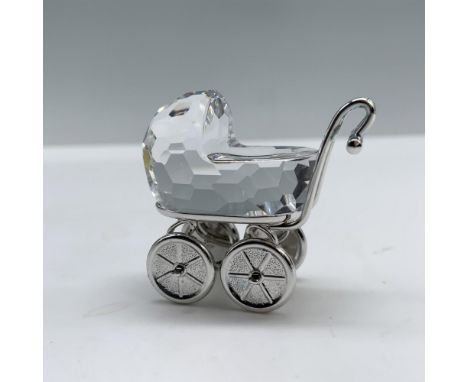 A crystal carriage, adorned with a rhodium frame, handles, and wheels. Swarovski backstamp. This item has its original box wh