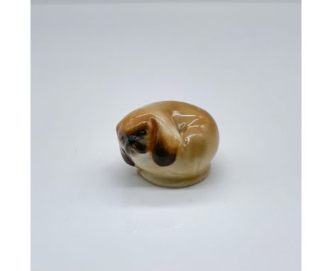 Hand painted porcelain figure of a curled up Chinese toy dog; pale brown glaze with dark brown highlights. Doulton backstamp.