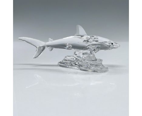 A clear crystal figure of a shark with melon-colored eyes that is swimming over some rocks. Swarovski backstamp. This item ha