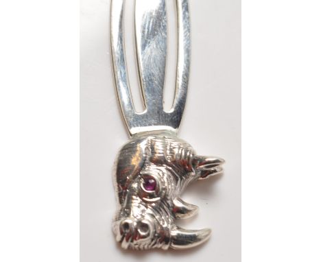 A stamped sterling silver book mark having a finial in the form of a tyrannosauruses head with with ruby glass eyes. Measures
