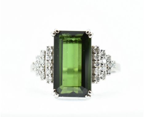 An 18ct white gold green tourmaline and diamond ring. The ring set with a green emerald cut tourmaline flanked by terraced se