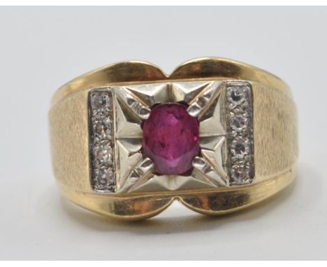 A 20th Century 14ct gold ring set with a central oval cut ruby flanked by four round cut diamonds with panelled textured shou