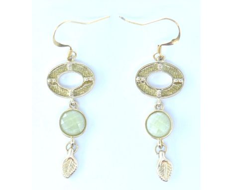 A pair of stamped 375 9ct gold drop earrings having pierced oval drops with clear enamel with faceted green stones and leaf m