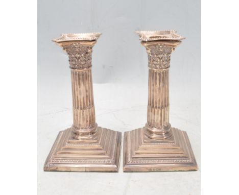 A pair of early 20th Edwardian silver hallmarked candlesticks. The two candlestick being modelled in Greek Corinthian column 