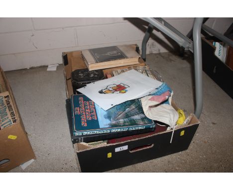 A box containing books, tins, flags, lamp shade etc.