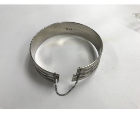 Vintage silver solid bangle with diamond cut finish with a twisted opening and safety chain. Hallmarked