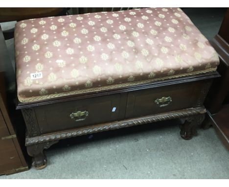 A mahogany ottoman type stool with an upholstered seat above two drawers on ball and claw feet