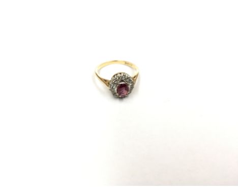 An 18ct Ladies ring set with a central ruby flanked by diamonds. Ring size M.
