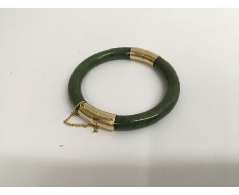 A jade bangle with unmarked gold clasp