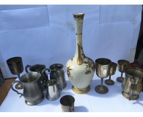 A collection of pewter cups and jugs alongside a ceramic vessel