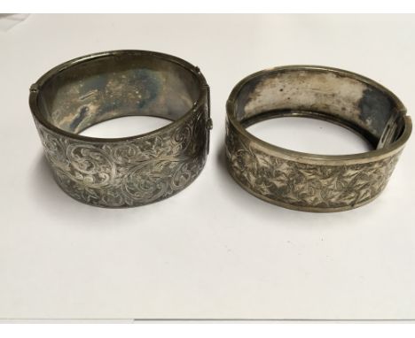 A wide silver bangle with scroll decoration Birmingham hallmarks and one other white metal bangle (2)
