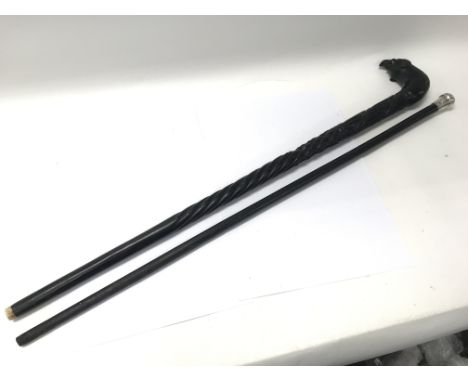 An ebony topped walking stick together with a silver topped walking stick.