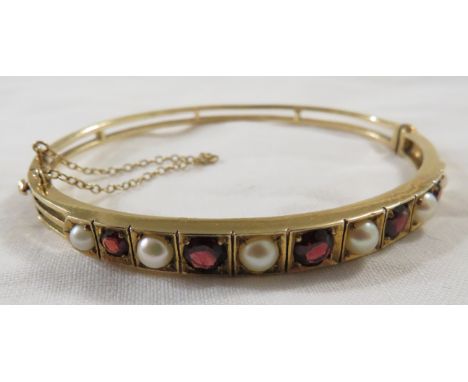 9 carat gold bangle set with six pearls and five graduated garnets, stamped 9 .375, safety chain, 14.5g, with a Mappin and We