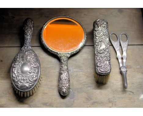 A silver mounted Hairbrush, matching hand mirror, a silver mounted clothes brush and a pair of plated grape scissors. 