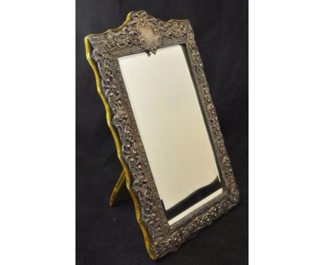 A bevel edge upright Table Mirror in embossed and chased silver frame, with a vacant cartouche and on an easel stand, 15" (39