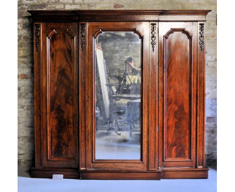 A Victorian mahogany break front Wardrobe with stepped cornice, enclosed by a centre mirror panelled door, the interior fitte