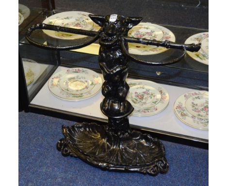 An ebonised cast metal stick stand, modelled as a dog with stick in mouth, above sea shell style insert to base, 60cm high x 